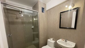 A modern bathroom with a glass-enclosed shower, a toilet, a sink, and a mirror. - Terrazas Suite (Lima)