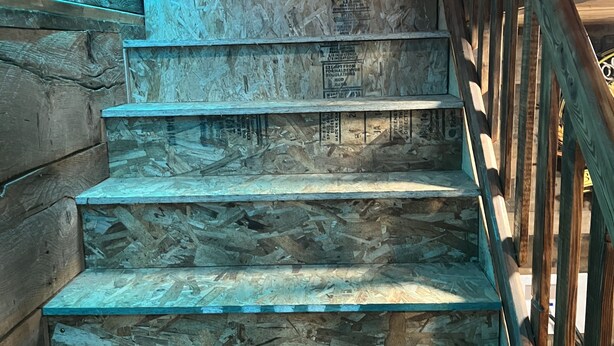 Una escalera de madera con barandilla de madera y una tira de luz azul en el lado izquierdo.