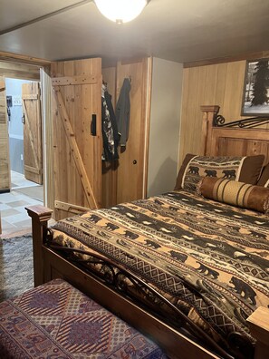 A bedroom with a wooden bed, a bench, and a wardrobe. - Beautiful Cabin located in the Blue mountain’s, pet friendly and many extras. (Weston)