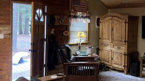 Interior acogedor de una cabaña con techo de madera, un sofá, una mesa y un aparador.