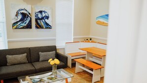 A living room with a sofa, coffee table, and a dining area with benches. - Spacious & Relaxing Mango Suite at Award-Winning Shangri-La Bed & Breakfast (West Bay)