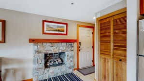 A stone fireplace with a wooden mantel, a framed picture above it, and a striped rug in front. - Adrift - Unit 6 (Chelan)