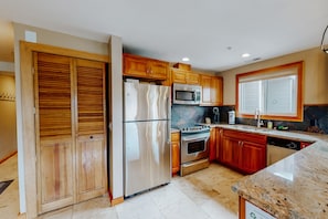 A kitchen with wooden cabinets, stainless steel appliances, and a granite countertop.