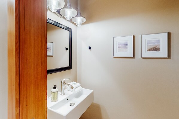A bathroom with a white sink, a mirror, and two framed pictures on the wall. - Adrift - Unit 6 (Chelan)