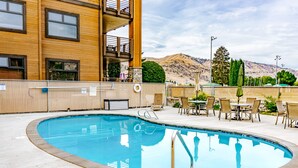 A pool area with a circular pool, outdoor seating, and a building with multiple windows and balconies. - Adrift - Unit 6 (Chelan)