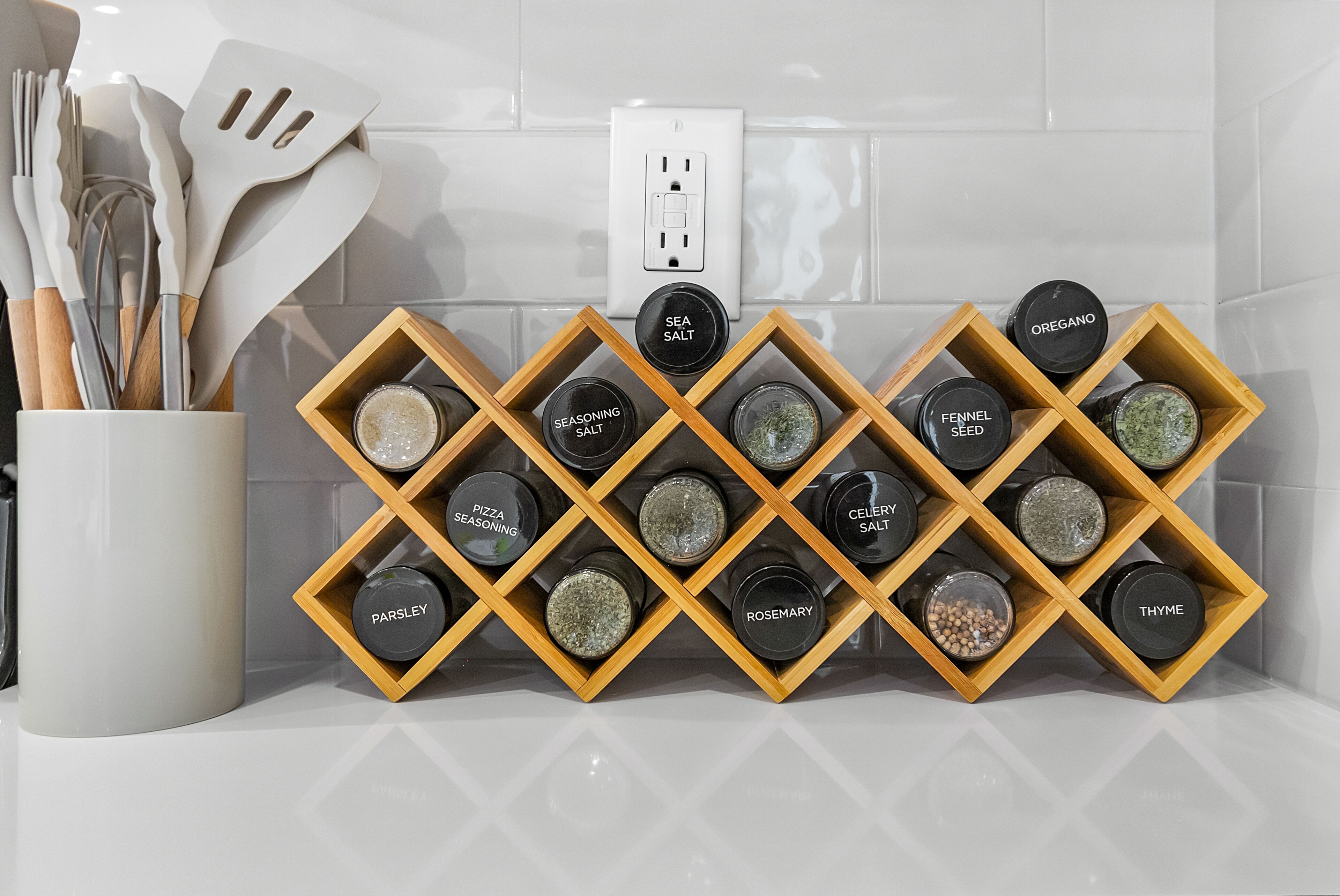 A kitchen with a spice rack holding jars labeled with various seasonings like sea salt, oregano, and thyme.