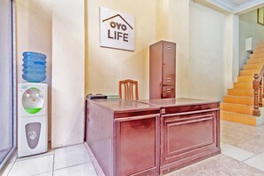 A reception desk with a water dispenser, a chair, and a cabinet in a hotel lobby. - OYO Life 2786 Puri Felicia 1 (Medan)