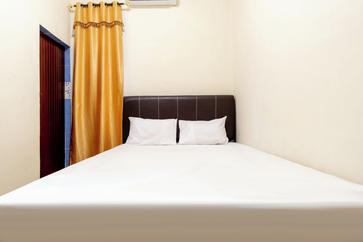 A single bed with a headboard, a yellow curtain, and a door with a blue frame.