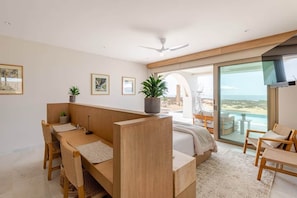 Ein modernes Schlafzimmer mit Bett, Schreibtisch und Blick auf den Strand.