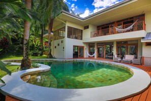 A two-story house with a large pool, surrounded by lush greenery and palm trees. - Rainforest Estate by Pura Villas (Quepos)