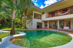 A two-story house with a swimming pool, surrounded by lush greenery and palm trees. - Rainforest Estate by Pura Villas (Quepos)