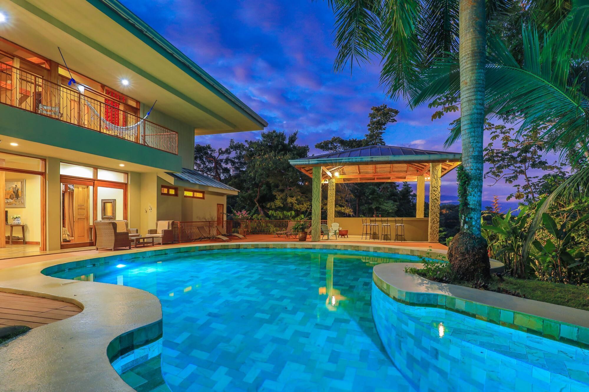 A two-story house with a swimming pool, outdoor seating, and a covered patio.