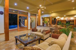 Un vaste espace de vie comprenant un canapé, une table basse et une vue sur une piscine et un espace extérieur.