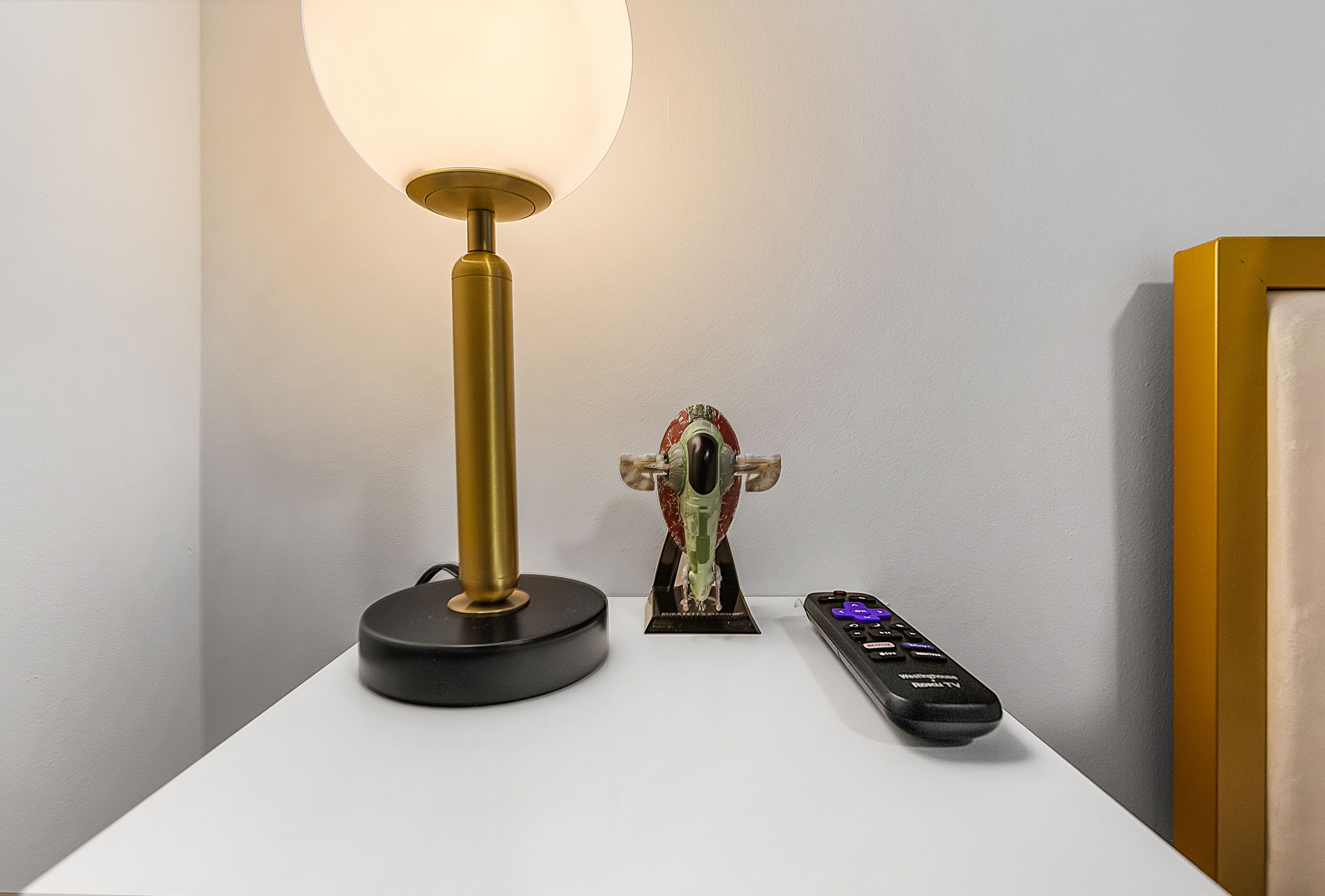 A table with a lamp, a small statue, and a remote control.