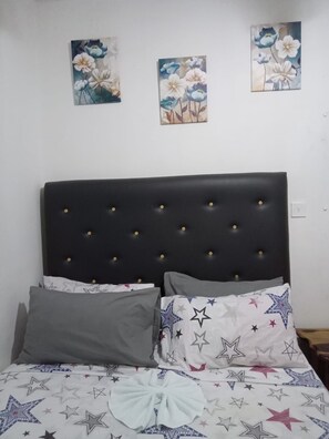 Restful retreat with a star-patterned bedspread and framed floral artwork.