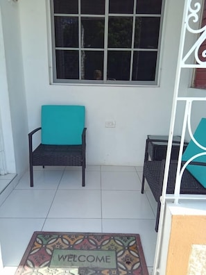 Relax in this serene outdoor space with a comfortable chair and a small table.