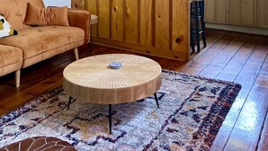 A cozy living room with a wooden accent wall, a round coffee table, and a patterned rug.