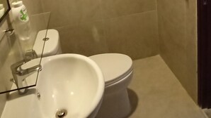 Un baño con lavamanos, inodoro y una toalla colgada en la pared.