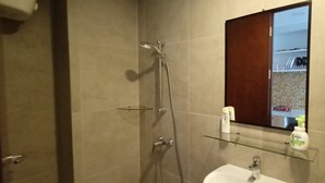 Un baño con ducha, lavamanos y espejo.