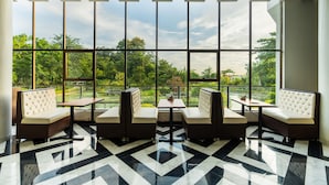 A modern interior with large windows, a geometric floor pattern, and seating arrangements. - Water Garden Resort & Spa (Tangail)