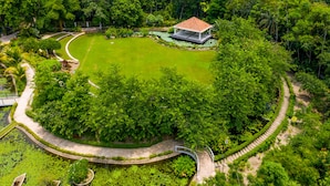 An aerial view of a lush, green park with a pavilion, winding pathways, and a pond. - Water Garden Resort & Spa (Tangail)