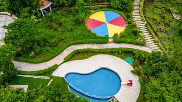 Relax in a serene garden setting with a swimming pool, play structure, and seating areas.