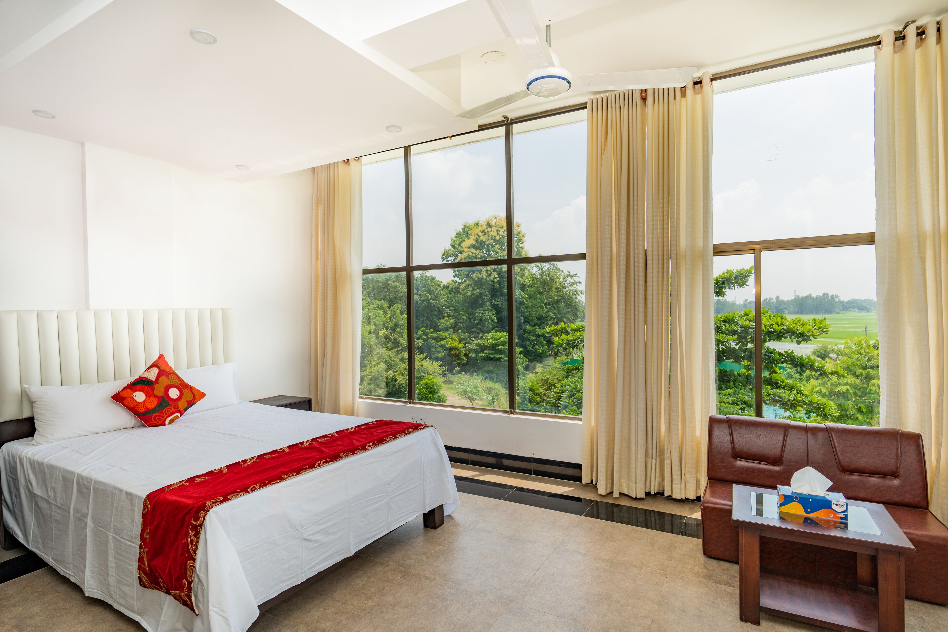 Une chambre d’hôtel avec un grand lit, un canapé et une vue sur la verdure environnante.