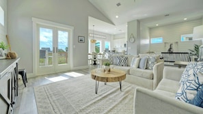 A spacious living room with a large window, a dining area, and a kitchen.