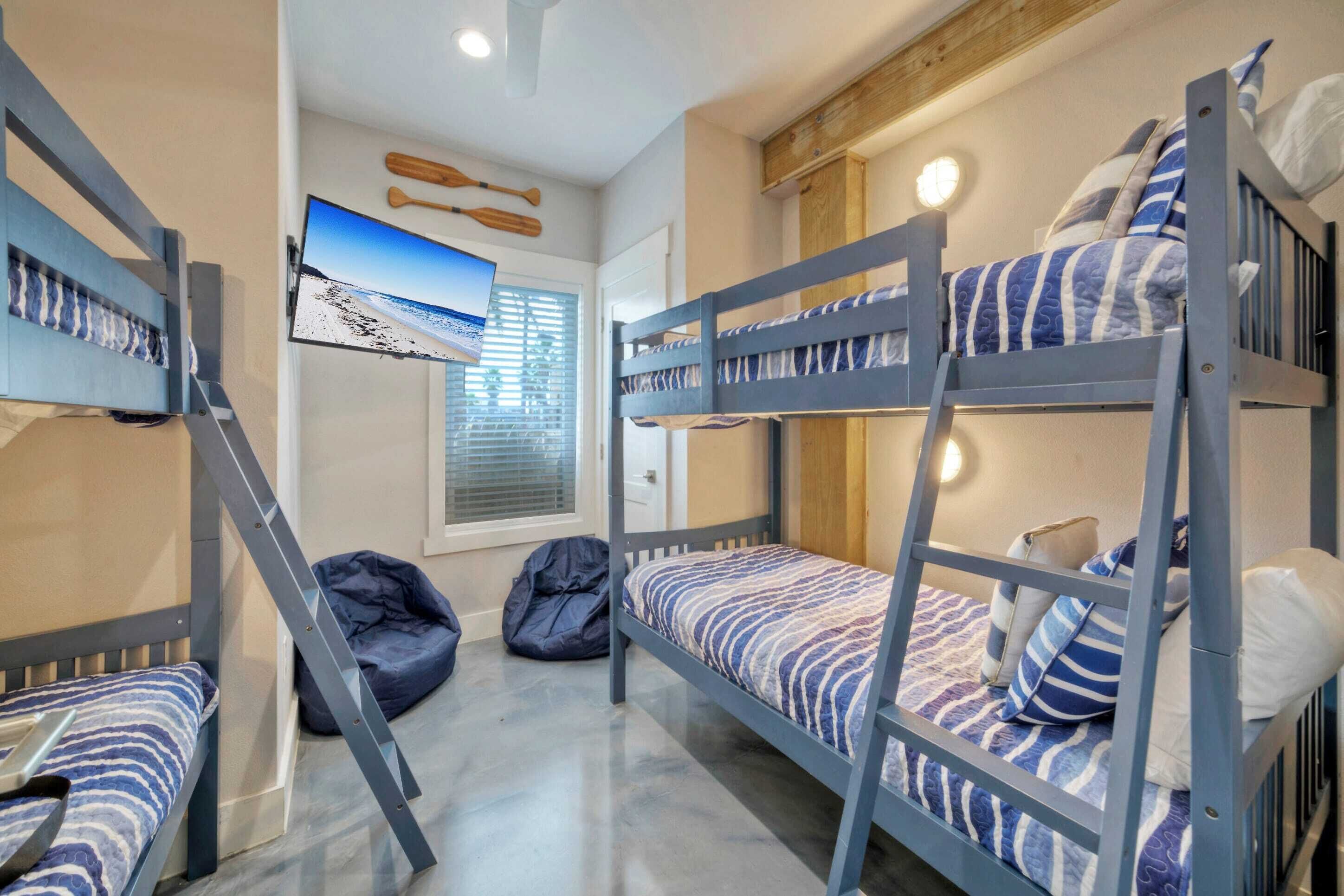 Habitación con literas, una escalera de madera, escritorio y un sillón de peluche.