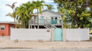 A two-story house with a white picket fence, a turquoise door, and a balcony. - Sea Glass Secrets by Avantstay 3 Mins to Beach (Key West)