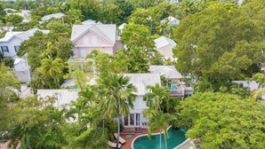 A residential area with a large house surrounded by lush greenery and a swimming pool.