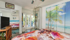 A room with a large tropical mural, a television, and a bed with a colorful headboard. - Monkey House by Avantstay Pool, by Duval Street (Key West)