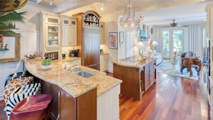 A spacious kitchen with a large island, wooden cabinets, and a chandelier. - Tennessee Williams by Avantstay Funky Design + Pool (Key West)