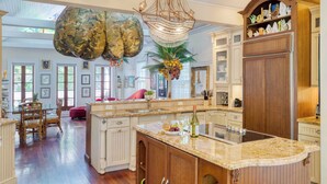 A spacious kitchen with a large island, wooden cabinets, and a decorative chandelier. - Tennessee Williams by Avantstay Funky Design + Pool (Key West)
