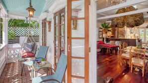 A spacious veranda with wicker furniture, a dining area with wooden chairs, and a bar with a large rock decoration. - Tennessee Williams by Avantstay Funky Design + Pool (Key West)