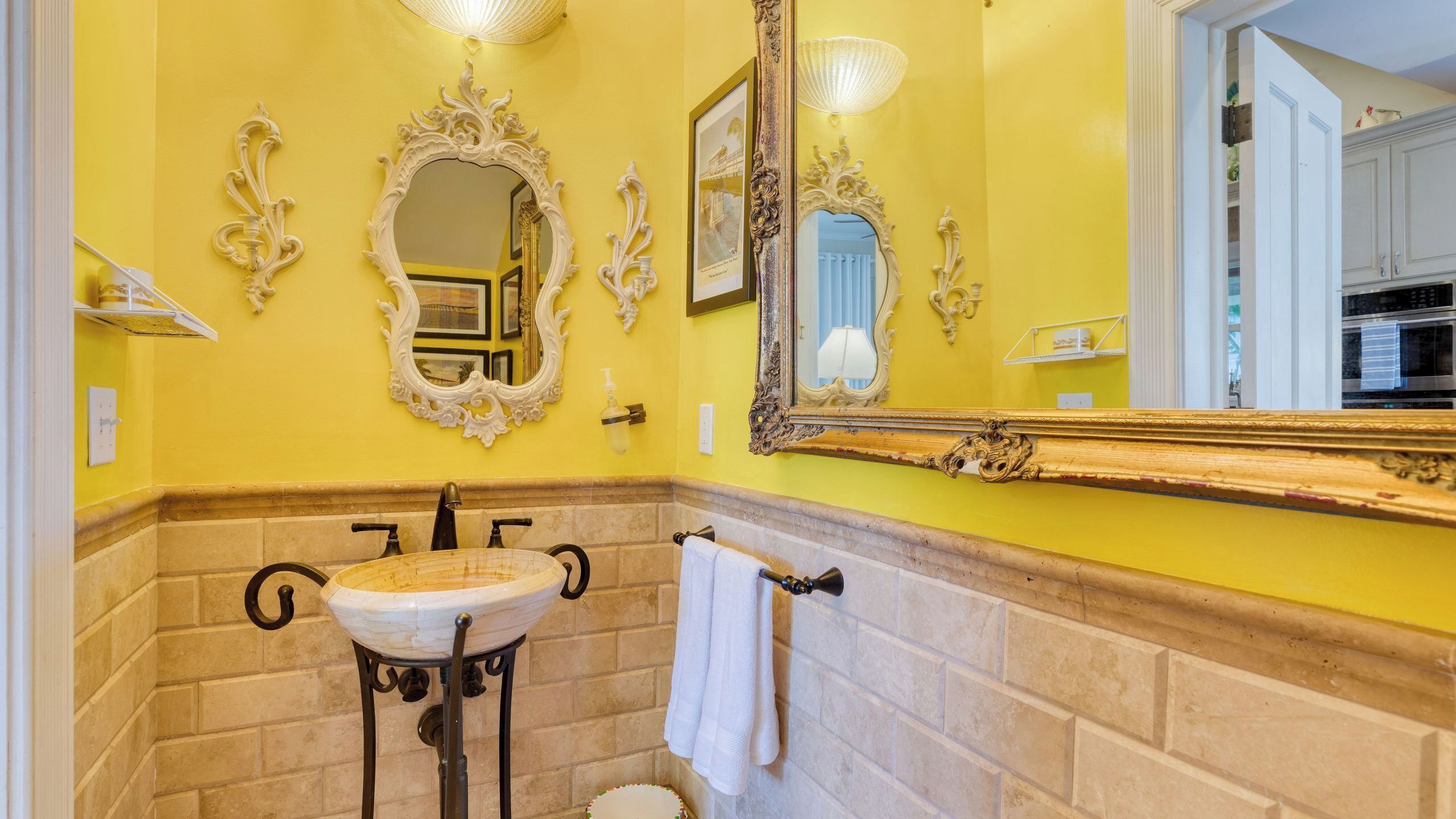 Un baño con un espejo grande, un lavamanos y un perchero para toallas.