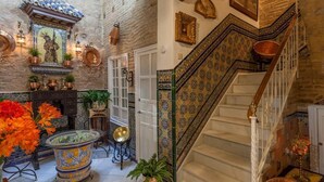 A traditional interior with a staircase, tiled walls, and decorative items. - Purasevilla Apartments. Casa Señorial Sevillana (Sevilla)