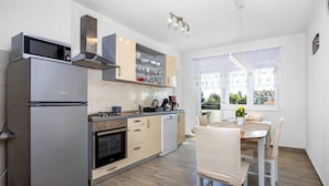 A modern kitchen with a built-in oven, microwave, and gas stove. There is a dining area with a table and chairs. - Apartment Ivana - Sea View, Pet Friendly (Fažana)