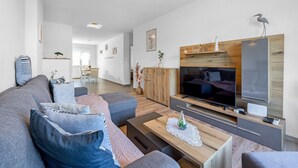 A modern living room with a large flat-screen TV, wooden cabinets, and a sofa with multiple cushions. - Apartment Ivana - Sea View, Pet Friendly (Fažana)