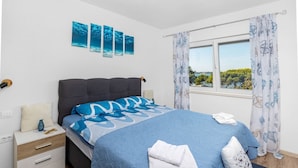 A bedroom with a bed, a nightstand, a window with curtains, and wall art. - Apartment Ivana - Sea View, Pet Friendly (Fažana)