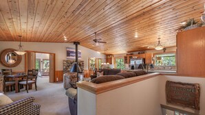 L’intérieur d’une cabane est doté d’un plafond en bois, d’un coin repas, d’un canapé et d’une cuisine avec des meubles en bois.