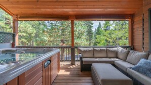 Une terrasse en bois avec un jacuzzi, un canapé et un banc rembourré.