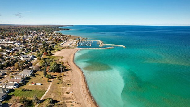 Luftaufnahme einer Küstenstadt mit Strand, klarem blauen Wasser und Wohngebieten.