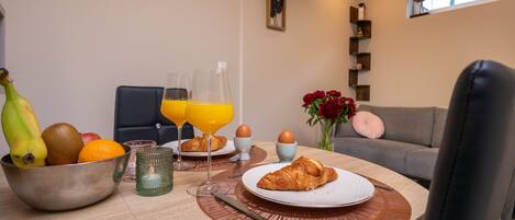 Een ontbijttafel met fruit, eieren en croissants.