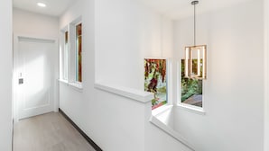 A hallway with white walls, a wooden floor, and a door at the end. - Jabba's Palace (Seattle)