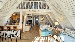 Un loft spacieux avec de hauts plafonds, un coin cuisine, un espace repas et un coin salon confortable avec un canapé et des fauteuils.