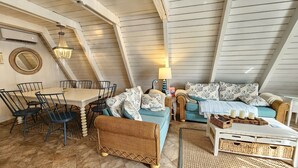 Une chambre à coucher confortable, aménagée en mezzanine, avec un coin repas, une grande fenêtre et un ventilateur de plafond.