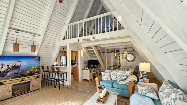 Un loft spacieux avec de hauts plafonds, un coin repas, une cuisine et un salon équipé d’une télévision et d’une cheminée.