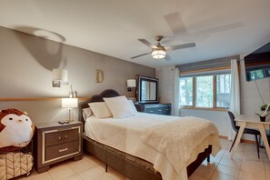 A bedroom with a bed, nightstand, lamp, TV, desk, and window. - Pelican Lake House w/ Boat Dock and Sauna! (Pelican Lake)