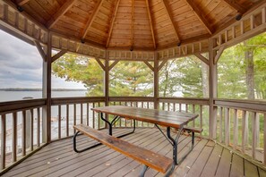 A wooden gazebo with a picnic table, surrounded by a wooden deck and overlooking a body of water. - Pelican Lake House w/ Boat Dock and Sauna! (Pelican Lake)